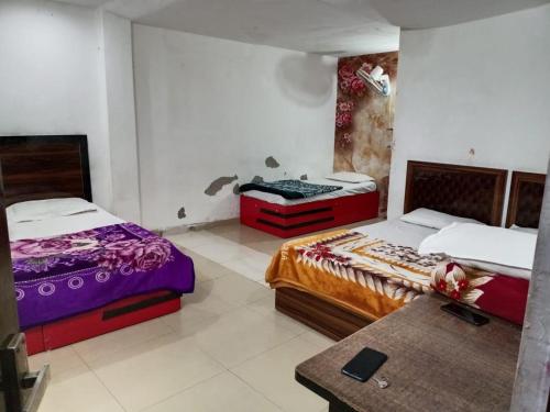 a room with two beds and a table in it at Mohit guest In in Vrindāvan