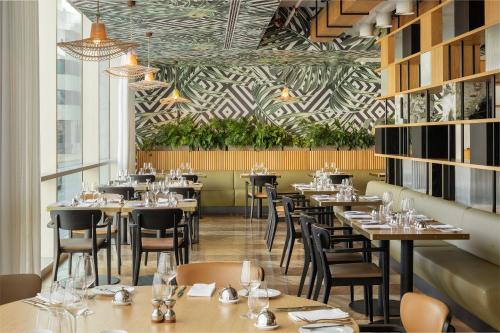 a restaurant with tables and chairs and plants at EPIC SANA Marquês Hotel in Lisbon