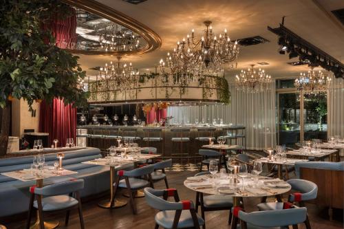 a restaurant with tables and chairs and chandeliers at EPIC SANA Marquês Hotel in Lisbon