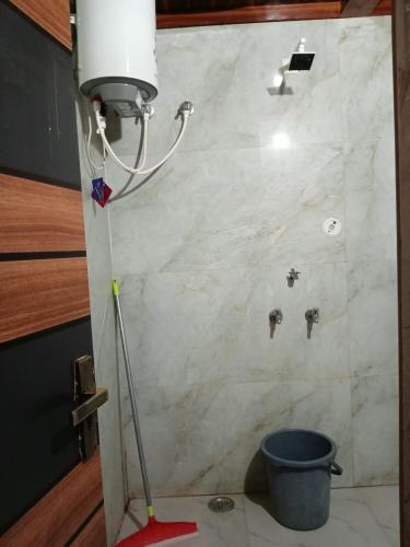 a bathroom with a white marble wall with a bucket at Mohit guest In in Vrindāvan
