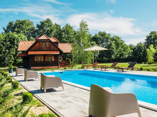 a pool with chairs and a house in the background at Moslavačka Priča Holiday Homes in Mala Ludina