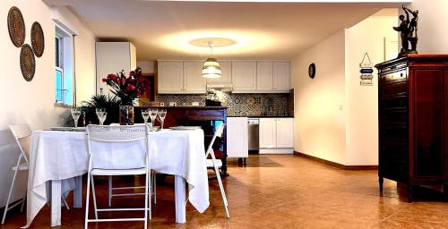 a kitchen with a table with white tables and chairs at Lazaro Beach House in Faro
