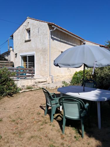 une table, deux chaises et un parasol dans l'établissement Modern one bedroom cottage, à Saint-Mandé-sur-Brédoire
