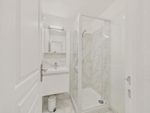 Un baño blanco con ducha y lavabo. en Face au port - 400m plage - Appart pour 2, en Arzon