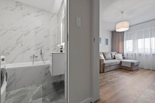 a white bathroom with a bath tub and a couch at ApartGo! P in Radom