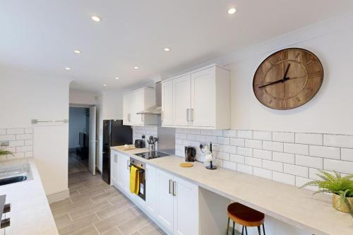 a kitchen with white cabinets and a clock on the wall at Central Stunning 3-Bed House - Free Parking in Sunderland