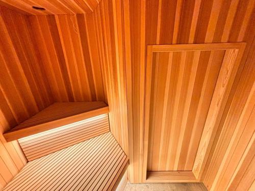 a small sauna with wooden walls and a door at MINI HOTEL totonoi ロウリュ式サウナのある静かな平屋 in Shimonoseki