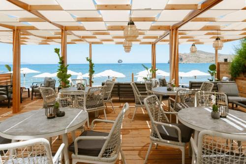 a restaurant with tables and chairs and the ocean in the background at Stavros Beachfront Suites in Nea Kydonia