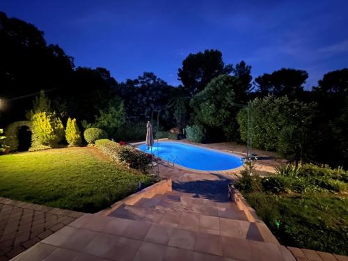 - une piscine dans un jardin la nuit dans l'établissement Villa Les Cyprés, à Flayosc