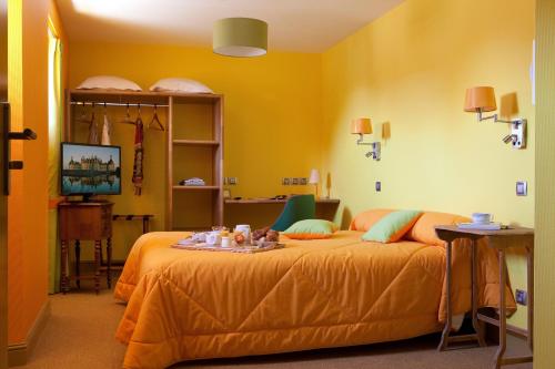 a yellow bedroom with a bed with a tray on it at Logis hôtel Ô en Couleur in Oucques