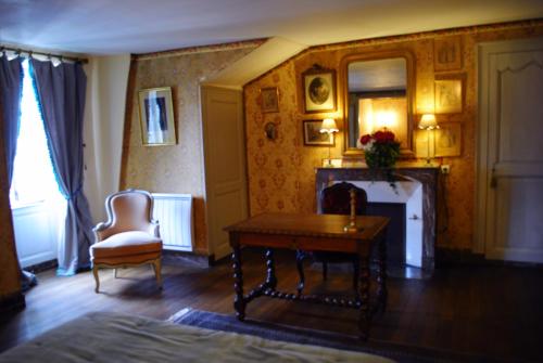 a room with a table and a chair and a fireplace at Le Ragois in Richelieu