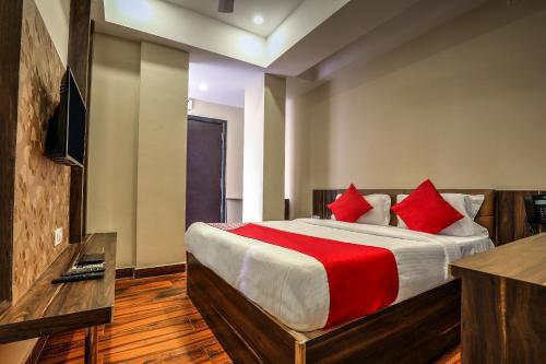 a bedroom with a large bed with red pillows at Capital O SKY GRAND in Hyderabad