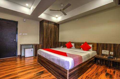 a bedroom with a bed with red pillows on it at Capital O SKY GRAND in Hyderabad