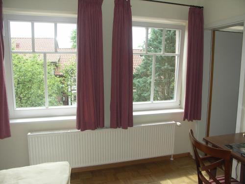 a room with two windows with red curtains at Dreimädelhaus - Kirchseelte in Kirchseelte