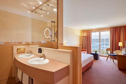 ヴェスターブルクにあるGolf- und Sporthotel Wiesenseeのホテルのバスルーム(シンク2台、ベッド1台付)