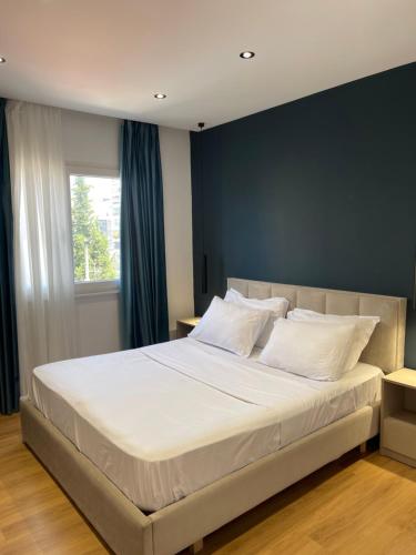 Un dormitorio con una cama grande con almohadas blancas. en Central Modern Apartment, en Tirana