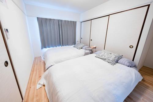 two beds in a small room with a window at SETO8 House in Seto