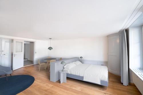 a white bedroom with a bed and a table at La Sauvage in Fribourg