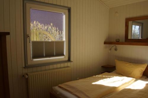 a bedroom with a bed and a window at Kinderfreundliches 6 Personen Ferienhaus mit zwei Duschen und Toiletten, Sauna, Whirlpool und einem Wintergarten mit Kaminofen in Otterndorf in Otterndorf