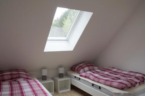 two beds in a room with a window at 6 Personen Ferienhaus mit zwei Duschen und Toiletten, Sauna, Whirlpool und Kaminofen in Otterndorf in Otterndorf
