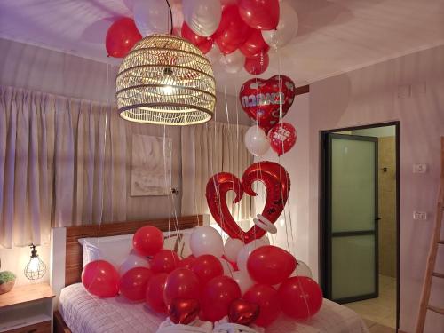 a bed with red and white balloons in a room at פרדייז ברמה in Had Nes