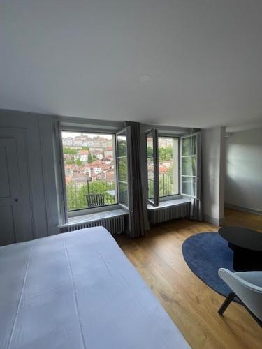 a bedroom with a large bed and two windows at La Sauvage in Fribourg