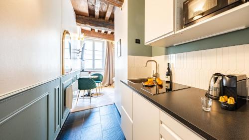 une cuisine avec des armoires blanches et un comptoir dans l'établissement L'Écrin des Vignes - Appartement de Charme en Hyper-Centre, à Dijon