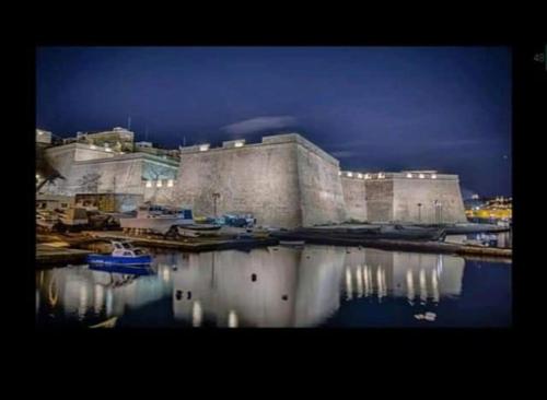 a large building with its reflection in the water at Seafront 1 bedroom Maisonette in Kalkara