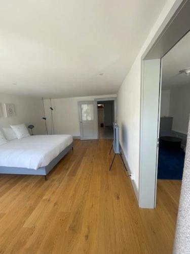 a bedroom with a white bed and a wooden floor at La Sauvage in Fribourg