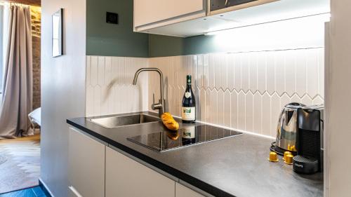 - une cuisine avec un évier et une bouteille de vin dans l'établissement L'Écrin des Vignes - Appartement de Charme en Hyper-Centre, à Dijon