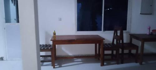 a table and two chairs and a desk and a window at Maga Apartment in Kinyasini