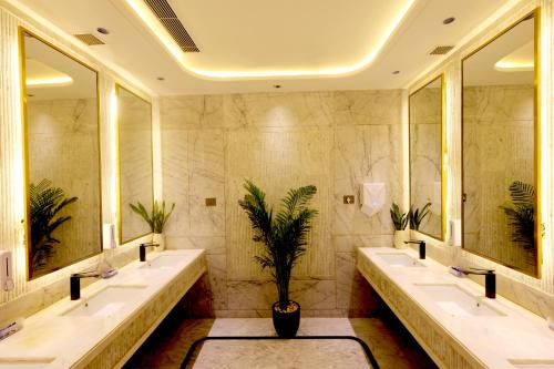 a bathroom with three sinks and a potted plant at The Tivoli New Delhi in New Delhi