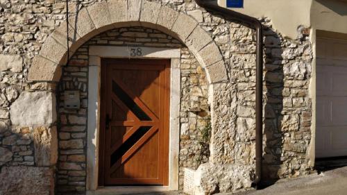 un edificio in pietra con una porta in legno e un arco di Filira Medulin a Medulin