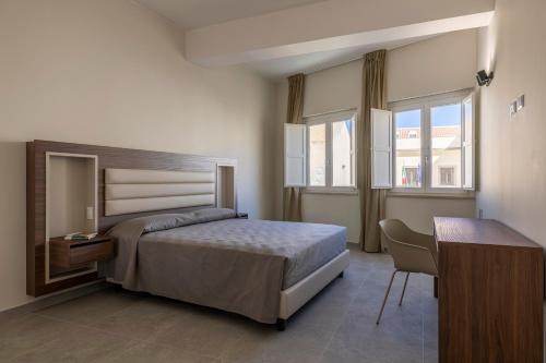 a bedroom with a bed and a desk and windows at Jolanda Sea Breeze in Trapani