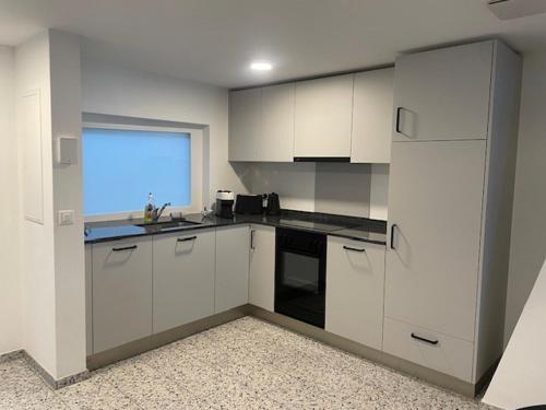 an empty kitchen with white cabinets and a window at La Sauvage in Fribourg