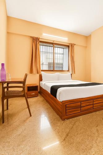 a bedroom with a bed and a table and a window at Hotel Parvat View in Pune