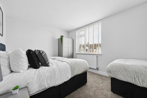 a bedroom with two beds and a window at NEW! Sleek & Spacious House by Clarendon Stays, Driveway Parking, WiFi, Smart TV in Allesley
