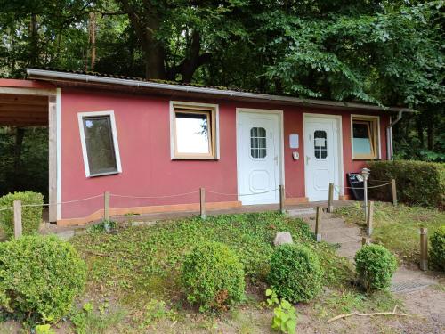 a red house with white doors in a yard at !Nur Stellplatz! Wohnwagen- & Mobil und Zelt Stellplatz "122", an der Mecklenburger Seenplatte in Fürstenberg-Havel