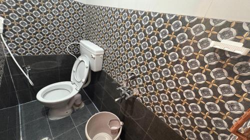 a bathroom with a toilet and a tiled wall at SHI's Agam Bed & Breakfast at Chennai in Chennai