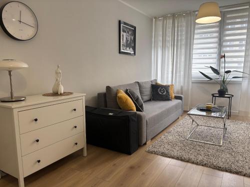 a living room with a couch and a clock on the wall at Apartament Rodzinny - Classic Olszowa in Włocławek