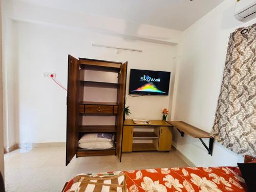 a small room with a desk and a tv on the wall at SHI's Agam Bed & Breakfast at Chennai in Chennai