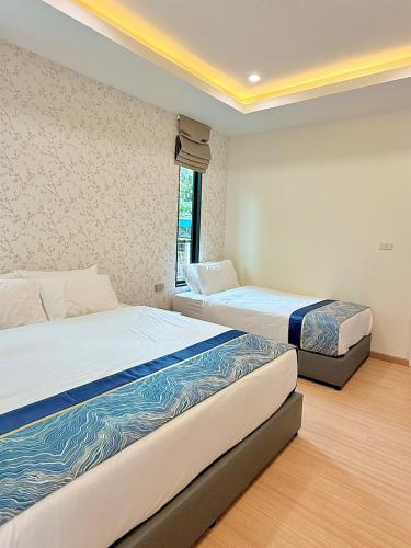 a bedroom with two beds and a window at The Swan Pool Villa Hatyai เดอะสวอน พูลวิลล่าหาดใหญ่ in Ban Kohong