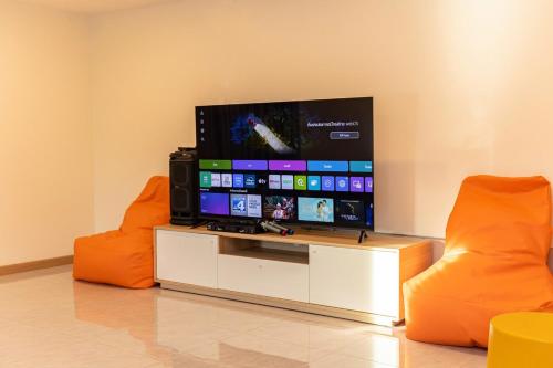 a living room with two orange chairs and a flat screen tv at The Swan Pool Villa Hatyai เดอะสวอน พูลวิลล่าหาดใหญ่ in Ban Kohong