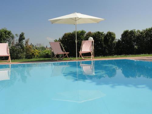 two chairs and an umbrella next to a swimming pool at Poggio Novello in Peccioli