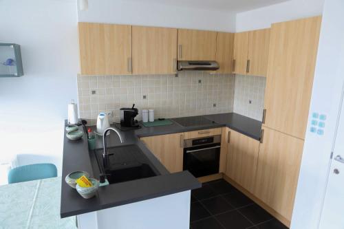 a kitchen with wooden cabinets and a sink at Harbour View Stay - Stylish apartment with stunning views in the marina of Zeebrugge in Zeebrugge