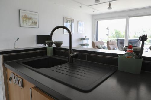 a kitchen sink with a black counter top at Harbour View Stay - Stylish apartment with stunning views in the marina of Zeebrugge in Zeebrugge