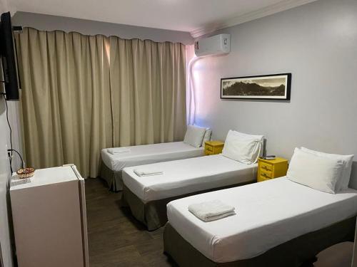 a hotel room with three beds and a purple light at Hospedaria Santiago in Teresópolis
