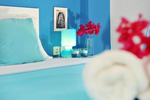 a blue room with a bed with red flowers on it at Aiolis Studios in Porto Koufo