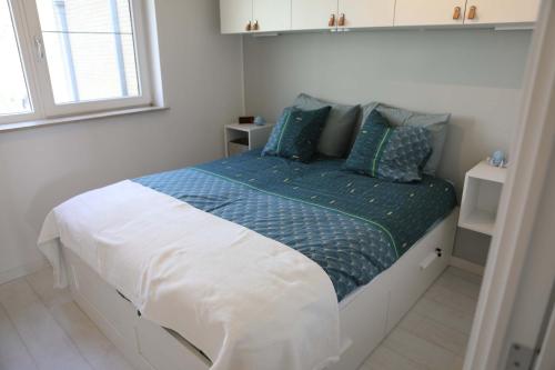 a bedroom with a bed with a blue and white comforter at Harbour View Stay - Stylish apartment with stunning views in the marina of Zeebrugge in Zeebrugge