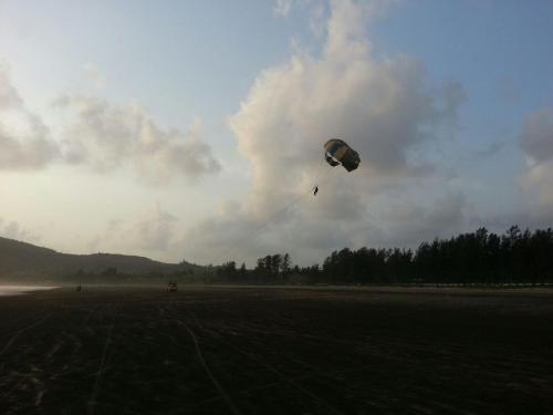 a person is flying a kite in a field at Tendulkar Beach Resort in Diveagar